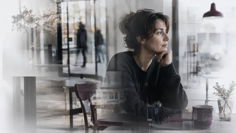 Witness reflecting on a remembered event behind glass
